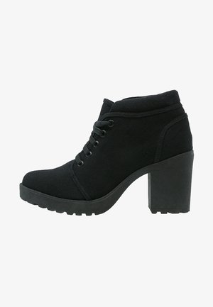 Bottines noires en tissu texturé avec un talon épais, dotées d'un bout arrondi et d'un laçage sur le devant. Semelle crantée pour une meilleure adhérence.