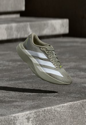 Ελαφρύ παπούτσι για τρέξιμο σε ελαιώδη πράσινο με λευκές ρίγες, υφασμένο πάνω μέρος και διακριτικό ανθικό μοτίβο στη μύτη. Μαλακή σόλα για άνεση.