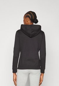 Mustmustäheline kapuutsiga sweatshirt, millel on sobiv disain ja pikad särgid. Siledat tekstuuri, soonikuga ääristust ja mansettide detaile on näha tagantvaates.