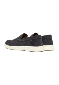Zapatos de ante gris oscuro tipo slip-on con una textura suave, suela de goma ligera y un diseño minimalista. Cuenta con un sutil detalle de marca.