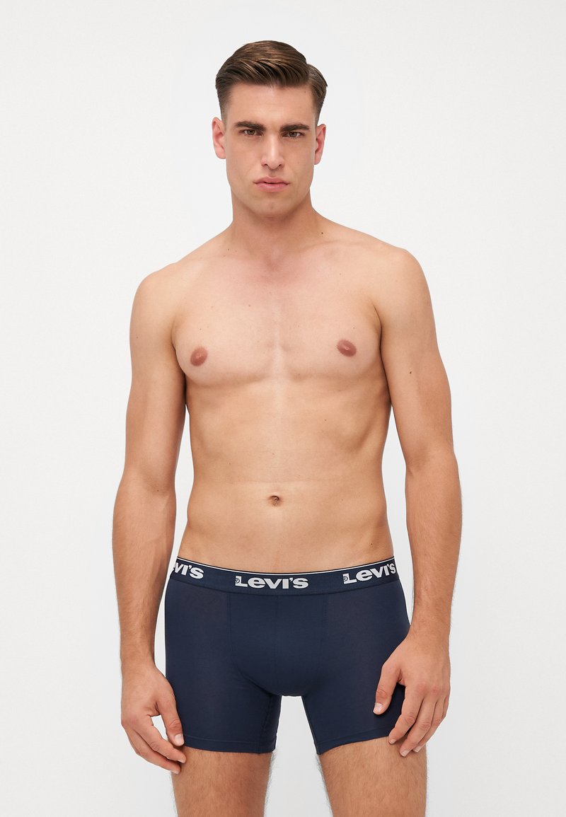 Sötétkék boxer alsónadrág fehér Levi's logóval a derekán. Puha anyag, testhezálló kialakítás, combközép hosszúság.