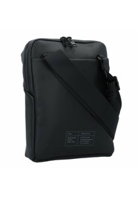 Borsa a spalla nera realizzata con materiali sostenibili, dotata di chiusura con zip, tracolla regolabile e un'etichetta con i dettagli del modello.