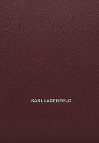 Portafoglio in pelle bordeaux con texture granulosa e dettagli del logo in argento, caratterizzato da un design minimalista e linee pulite.