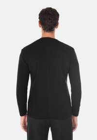 Maglione nero lavorato a maglia con scollatura rotonda e maniche lunghe. Presenta un tessuto testurizzato e una cucitura dritta che scende lungo la schiena.