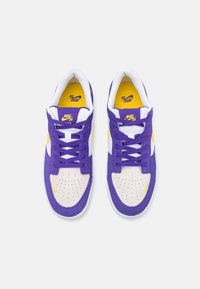 Baskets violettes et blanches avec des accents jaunes, dotées de détails perforés, de lacets plats et d'un col rembourré pour le confort.