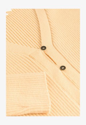 Ribbed, light peach cardigan with a V-neck, featuring two black buttons and a soft texture. Includes one open pocket on the sleeve.