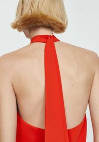 Rode halterjurk met een lage rug, voorzien van een brede strik om de hals. Soepele, lichtgewicht stof met een slanke silhouet en minimale details.