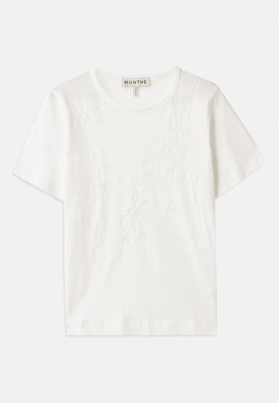 Camiseta de algodón blanca con mangas cortas, que presenta un diseño de bordado floral en la parte delantera y un escote redondo.