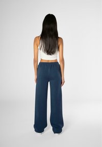 Pantalones de chándal anchos de color azul marino con una cinturilla elástica, fabricados en una tela suave, combinados con una camiseta crop blanca.