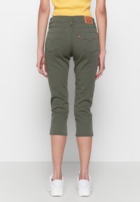 Oliwkowe jeansy capri o prostym kroju, z dwiema tylnymi kieszeniami z zaokrąglonym przeszyciem oraz skórzaną metką z logo w pasie.