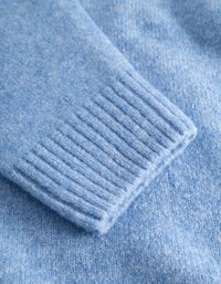 Ljusblå stickad tröja med en strukturerad, mjuk yta. Har ribbade muddar och en slät kroppstextil som framhäver dess mysiga utseende.