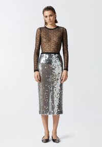 Black sheer long-sleeve top with logo pattern; silver sequin midi skirt; flat black shoes; simple design, form-fitting silhouette.