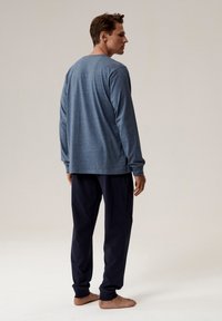 Granatowe spodnie piżamowe oraz długi rękaw w odcieniu heather blue, obie części wykonane z miękkiego materiału, o luźnym kroju i okrągłym dekolcie.