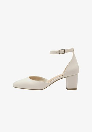 Escarpin en cuir blanc avec bout pointu, bride à la cheville et talon carré. Texture lisse et design minimaliste. Semelle plate avec un talon court.
