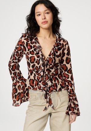 Leopard print blouse with ruffled neckline and sleeves, featuring shades of brown, black, and orange on a beige background. Ties at the front.