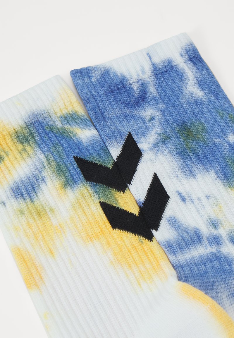 Calcetines de tie-dye coloridos que presentan tonos azules, amarillos y verdes, con textura acanalada y acentos del logo en forma de chevron en negro.