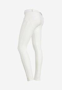 Pantaloni bianchi aderenti realizzati in tessuto morbido con vita medio-alta, caratterizzati da cuciture laterali discrete e due tasche posteriori.