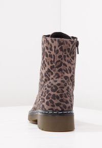 Botín hasta el tobillo con estampado de leopardo en ante marrón y negro, suela de goma marrón y cremallera lateral, mostrado desde la parte posterior sobre una superficie blanca.