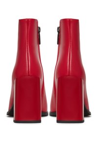 Bottes rouges à talons hauts avec une texture brillante, des talons carrés blocs et une fermeture éclair latérale pour un enfilage facile.