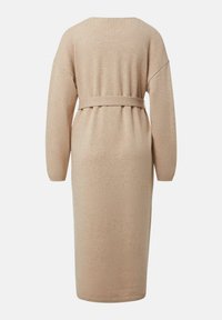 Beżowa dzianinowa sukienka o luźnym kroju, z długimi rękawami i paskiem w talii. Materiał jest miękki, a długość sięga połowy łydki.
