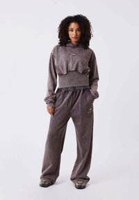 Sudadera gris corta con cordón, combinada con pantalones de pierna ancha a juego. Ambos confeccionados en una tela suave, con detalles de marca sutiles.