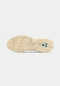 Sole della scarpa in bianco sporco con una superficie in gomma testurizzata. Presenta accenti blu e un design imbottito per trazione e supporto.