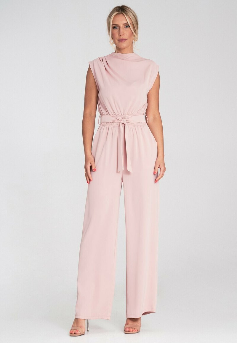 Jasnoróżowy kombinezon z wysoką szyją, rękawami na ramionach, elastycznym pasem i szerokimi nogawkami. Gładki materiał z wiązanym przodem.