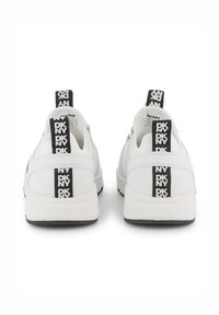 Baskets blanches avec une surface texturée, dotées d'un talon arrière de marque noir et d'une semelle robuste. Design simple avec une forme épurée.