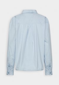 Camicetta azzurra a maniche lunghe con colletto a punte, piega sul retro e polsini con bottone. Realizzata in tessuto di cotone liscio.