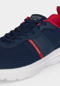 Тъмносиня и червена маратонка Jack & Jones с бяла подметка, горна част от мрежа, тъмносини връзки и брандиран етикет на езика и отстрани.