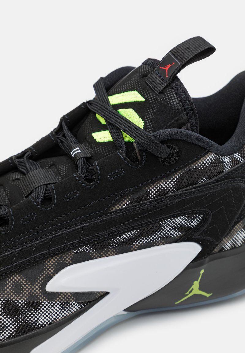 Zapatillas deportivas negras con detalles de malla y gamuza, con acentos en verde neón, una suela blanca y un logo Jumpman negro en el talón.