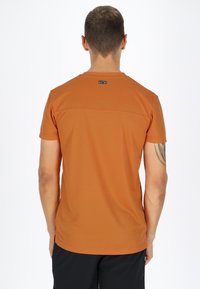 Kortærmet t-shirt med rund hals i ensfarvet brændt orange stof. Glat tekstur, med et lille mærke på bagsiden.