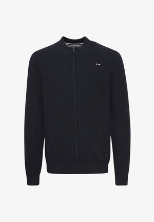 Marineblå zip-up cardigan med et strukturert mønster, ribbede mansjetter og linning. Har et lite logoemblem på brystet.