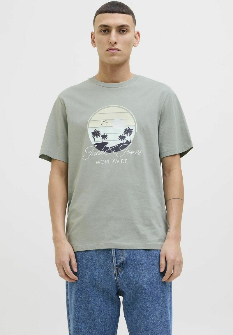Camiseta de algodón de color verde claro con un gráfico circular de playa que incluye palmeras, el nombre de la marca "Jack & Jones" y un corte relajado.
