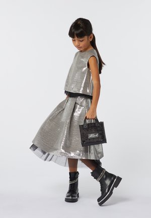 Zilverkleurige metallic crop top en een volle rok met een zwarte tule onderlaag. Zwarte combat boots en een kleine textuurhandtas met een logo.