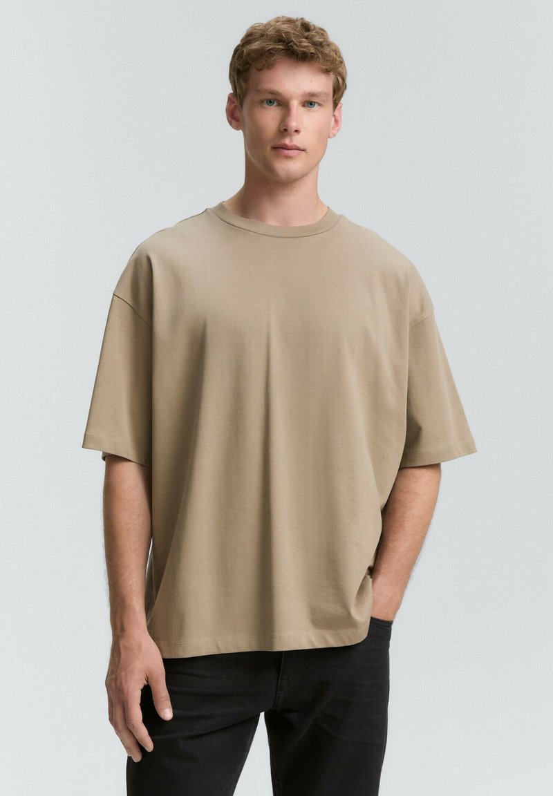Khaki oversize tričko vyrobené z mäkkej látky s okrúhlym výstrihom a krátkymi rukávmi, s voľným strihom a minimálnym švom.