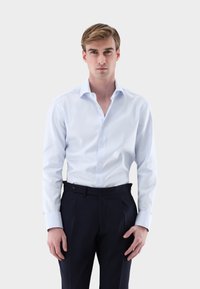 Hellblaues Hemd aus glattem Stoff mit spitzem Kragen, durchgehendem Knopfverschluss und langen Ärmeln mit kontrastierenden Manschetten, kombiniert mit dunkler Hose.