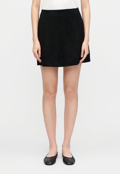 Black suede mini skirt with a straight cut. Features a smooth texture and discreet stitching, paired with simple black flats.