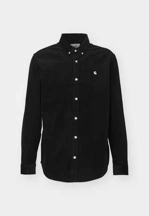 Camisa de pana negra con cuello abotonado. Presenta botones blancos y un pequeño logo en el pecho. Manga larga con puños abotonados.