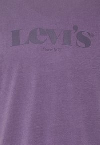 Camiseta morada hecha de tela suave, con el texto "Levi's" en letras negras en negrita y "Desde 1873" en un tamaño más pequeño debajo.