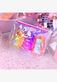 Trousse cosmétique transparente avec trois gels antibactériens colorés (orange, rose, bleu) à l'intérieur. La trousse présente un design holographique et une forme pointue.