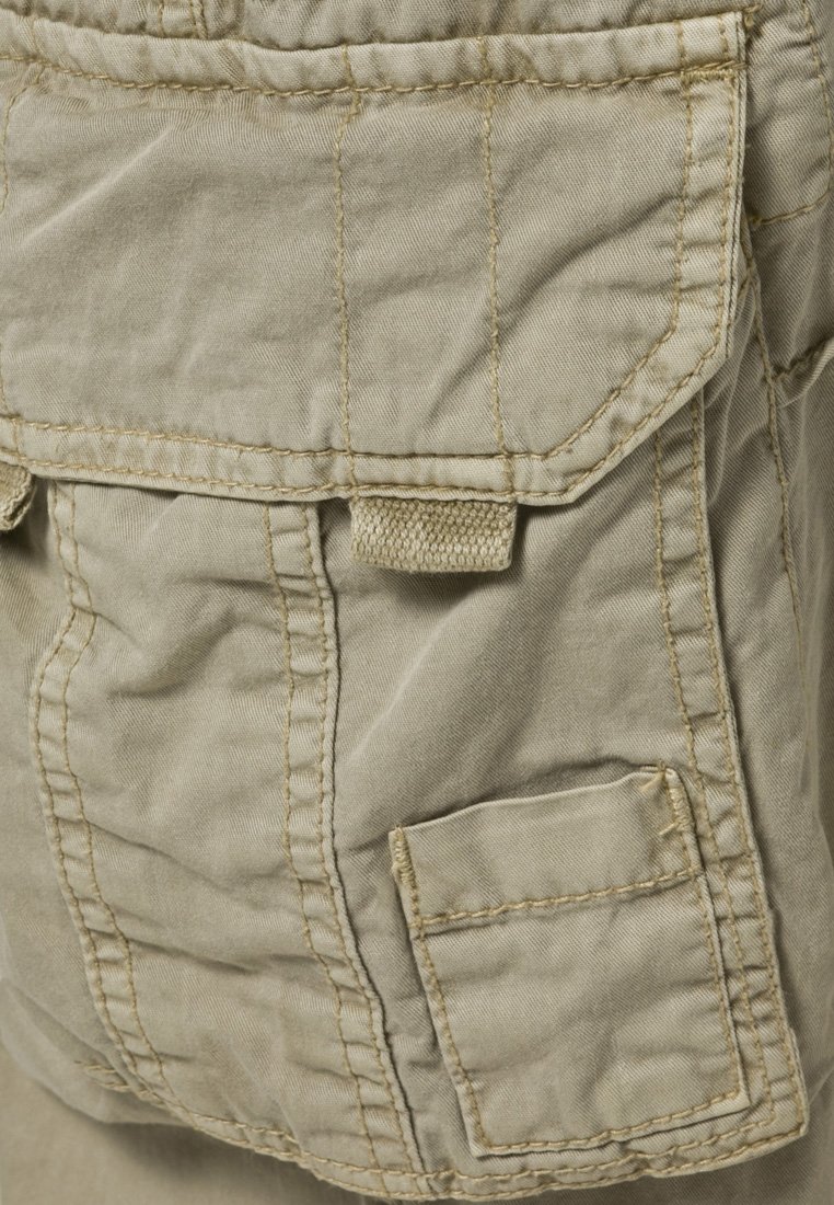 Beżowe szorty cargo z teksturowanej tkaniny, wieloma kieszeniami i widocznymi detalami szwów. Jedna kieszeń ma klapę i zapięcie na rzep.