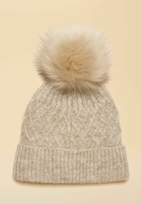 Beige knitted beanie hat featuring a textured diamond pattern and a large faux fur pom-pom on top. Ribbed cuff at the base.