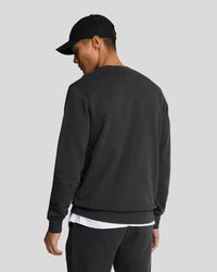 Black sweatshirt with a crew neckline and ribbed hem. Soft fabric texture, paired with a black cap. Side and back view are visible.