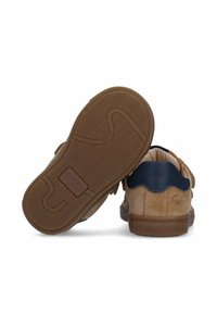 Scarpe per bambini in suede marrone con suole in gomma, una mostra il motivo del battistrada sul fondo e dettagli blu navy sul tallone.