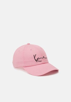 Casquette de baseball rose avec une visière incurvée et un logo en écriture noire à l'avant, sur un fond blanc uni.
