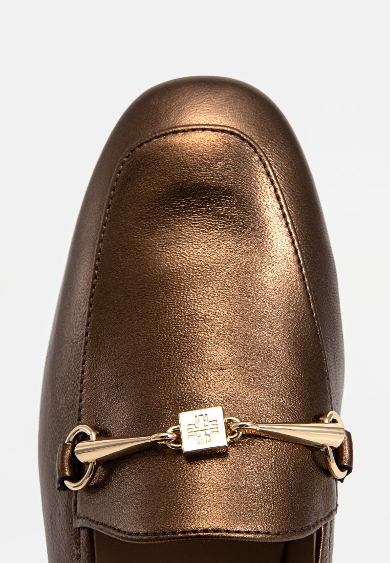 Brauner metallischer Lederloafer mit abgerundetem Zehenbereich, der ein goldfarbenes dekoratives Hardware-Detail über die Vorderseite aufweist. Glatte Textur.
