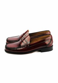 Mocasines de cuero marrón con acabado suave, costuras decorativas, puntera estilo mocasín y suela baja de goma negra.