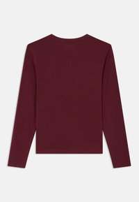 Bordó hosszú ujjú póló puha pamutból; hagyományos kerek nyakkivágással, slim fit szabással és sima, egyszínű textúrával.