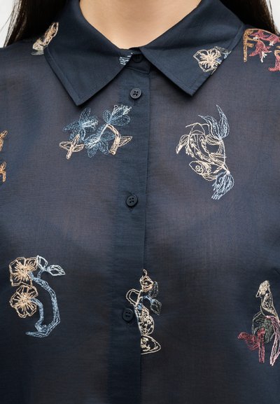 Chemise bleu marine boutonnée avec col pointu, ornée d'une broderie florale multicolore en tons bleu, crème et rose.